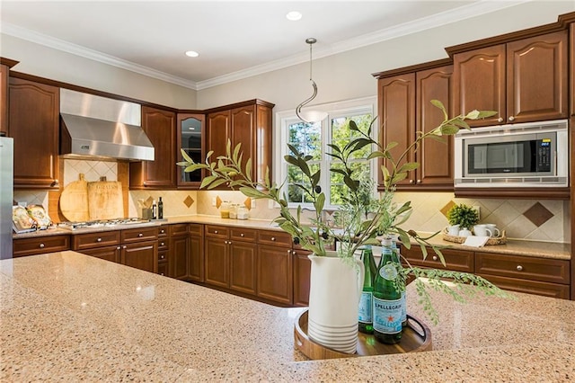 kitchen featuring appliances with stainless steel finishes, tasteful backsplash, light stone counters, decorative light fixtures, and wall chimney exhaust hood