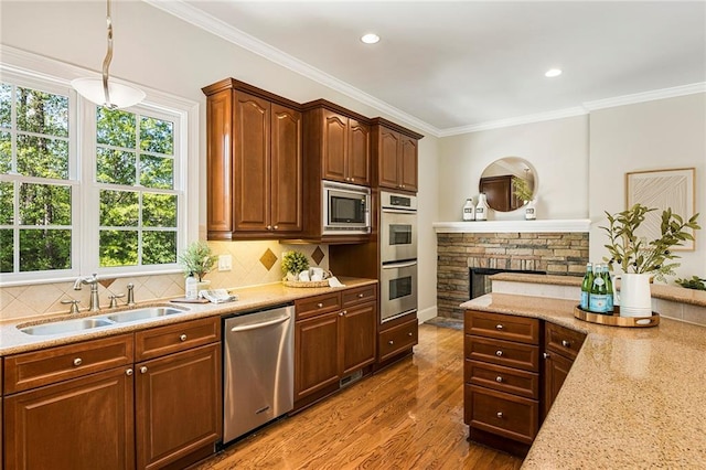 kitchen with dark wood-type flooring, stainless steel appliances, backsplash, a fireplace, and sink