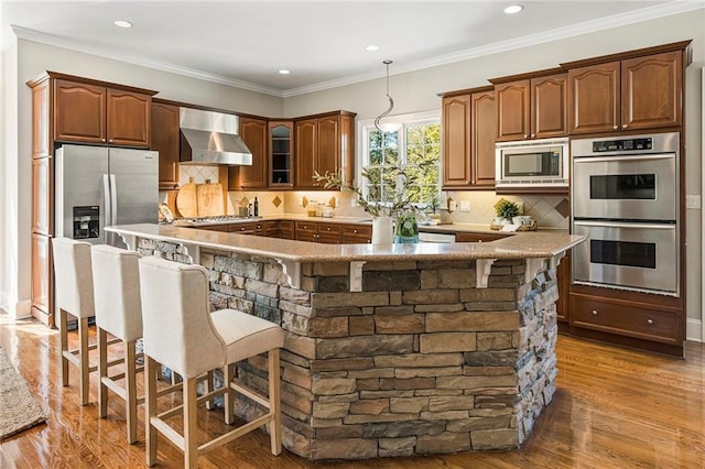 kitchen featuring appliances with stainless steel finishes, dark hardwood / wood-style flooring, wall chimney exhaust hood, and tasteful backsplash