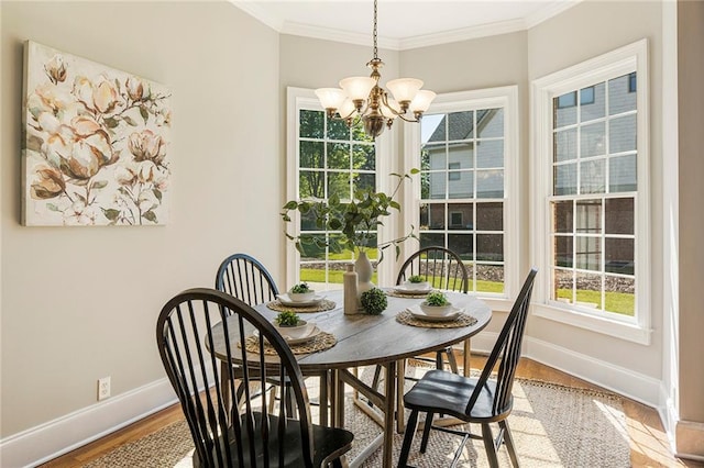 dining area with a chandelier, ornamental molding, and light hardwood / wood-style flooring