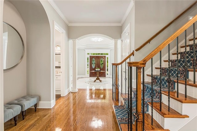 entryway with crown molding, decorative columns, and light hardwood / wood-style floors