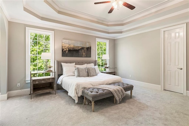 carpeted bedroom featuring multiple windows, ornamental molding, ceiling fan, and a raised ceiling