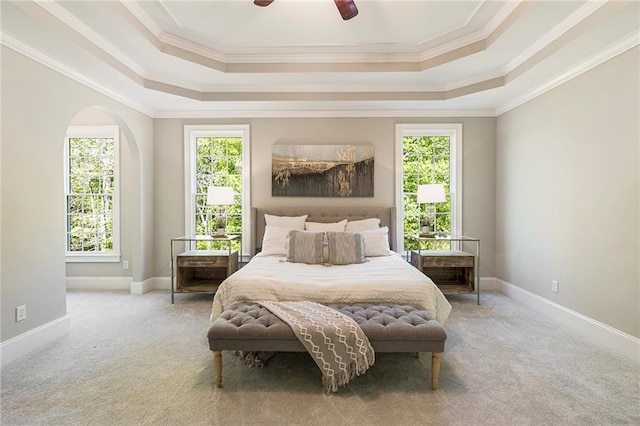 carpeted bedroom featuring ceiling fan, ornamental molding, and a tray ceiling