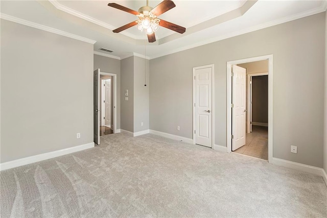 interior space featuring light colored carpet, a tray ceiling, ceiling fan, and crown molding