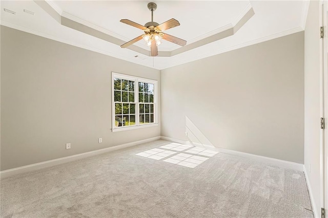 carpeted empty room featuring ceiling fan, ornamental molding, and a tray ceiling