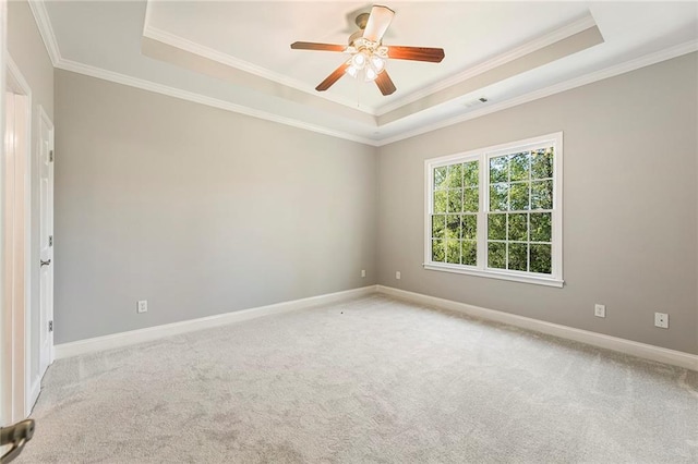 empty room featuring ceiling fan, crown molding, light carpet, and a tray ceiling