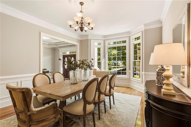 dining space with light hardwood / wood-style flooring, ornamental molding, and a notable chandelier