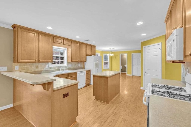 kitchen featuring a center island, hanging light fixtures, kitchen peninsula, white appliances, and a breakfast bar area