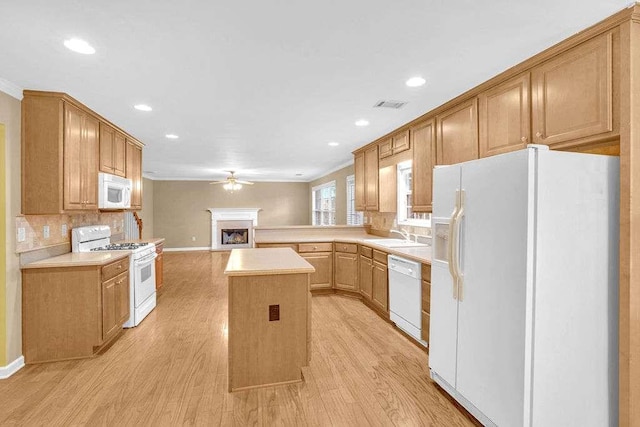 kitchen with white appliances, crown molding, sink, light hardwood / wood-style floors, and a kitchen island