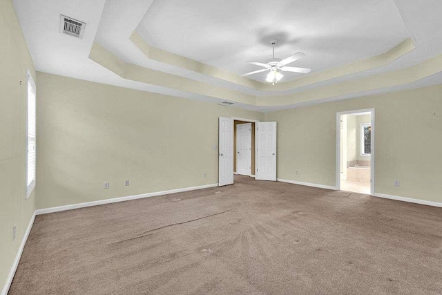 carpeted spare room with ceiling fan and a tray ceiling