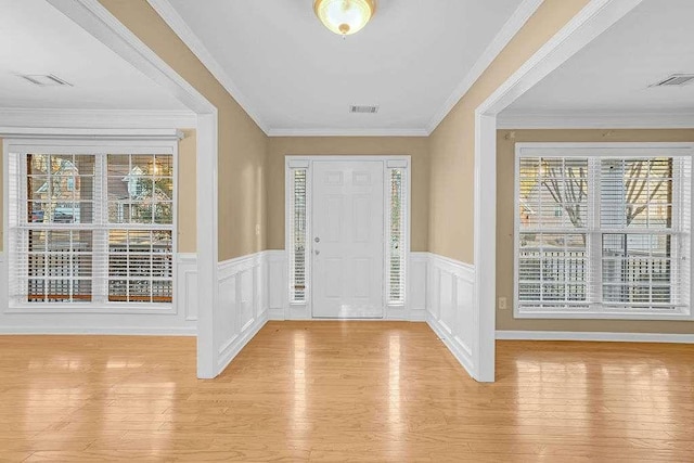 entryway with ornamental molding, light hardwood / wood-style floors, and a healthy amount of sunlight