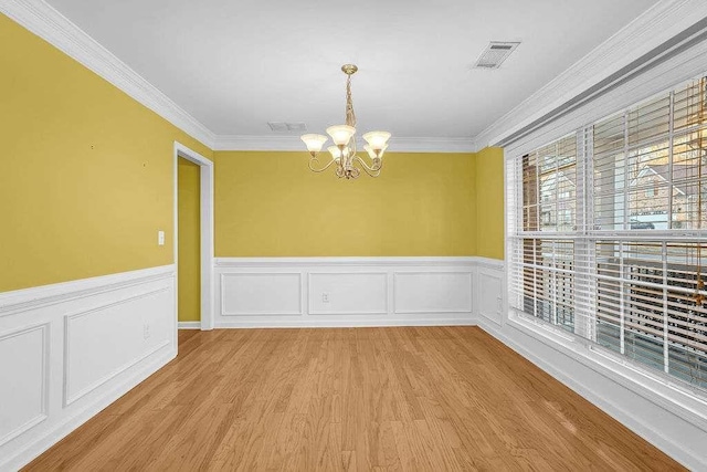 unfurnished dining area featuring light hardwood / wood-style flooring, crown molding, and a notable chandelier