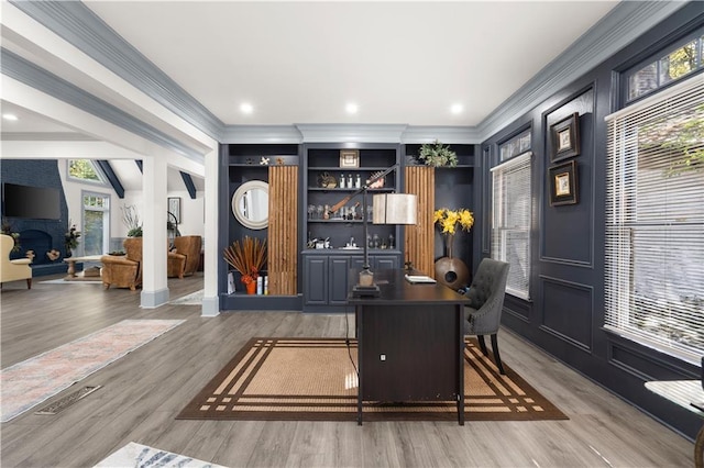 home office featuring recessed lighting, a fireplace, crown molding, and wood finished floors