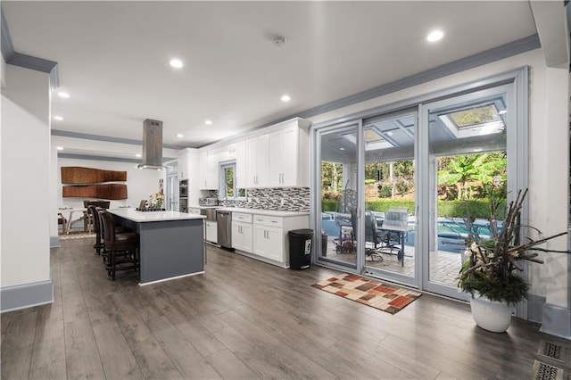 kitchen with island range hood, dark wood-style flooring, white cabinets, light countertops, and a center island