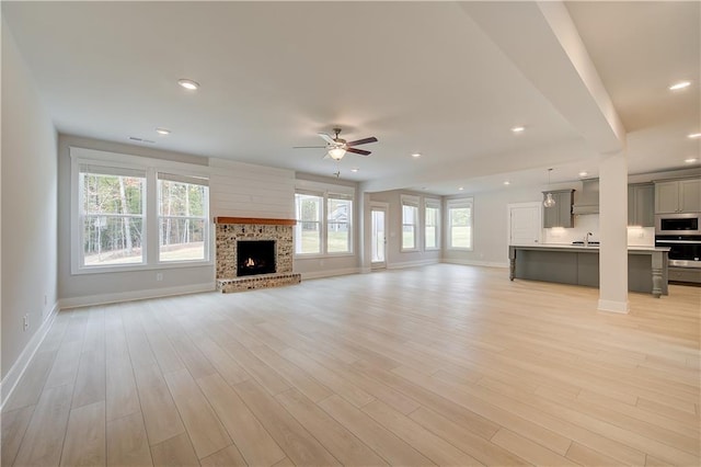 unfurnished living room with ceiling fan, light hardwood / wood-style floors, and sink