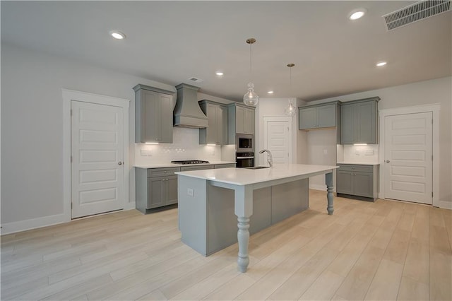 kitchen with appliances with stainless steel finishes, light hardwood / wood-style flooring, a breakfast bar area, and custom exhaust hood