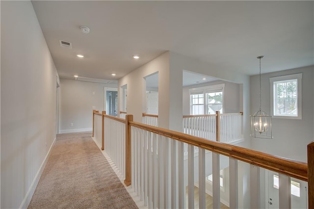 corridor featuring a notable chandelier and light colored carpet