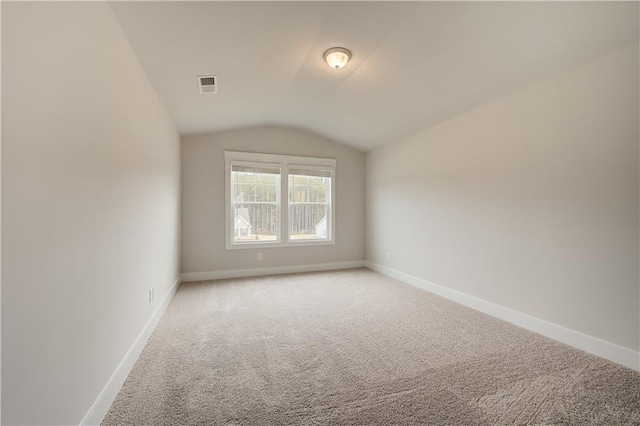 carpeted empty room featuring lofted ceiling