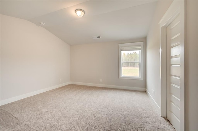 carpeted spare room with vaulted ceiling