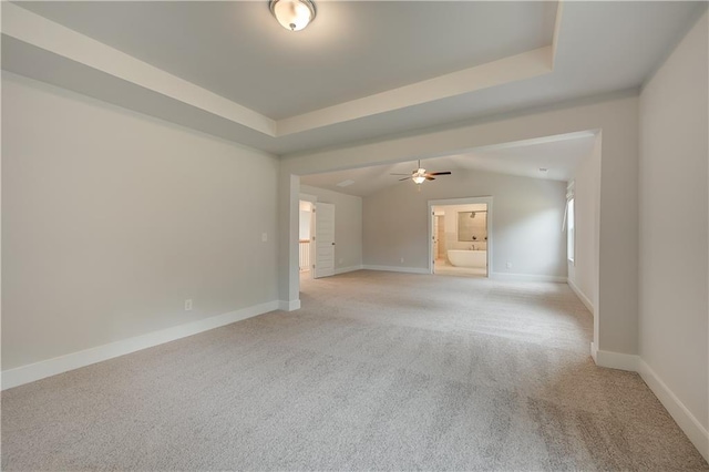 carpeted spare room with a raised ceiling and ceiling fan