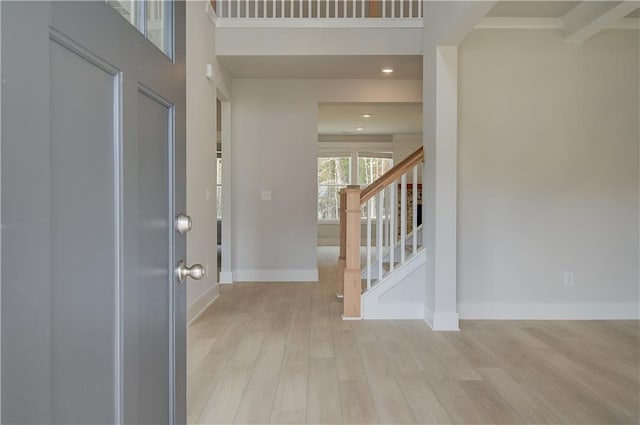 entryway with a towering ceiling and light wood-type flooring