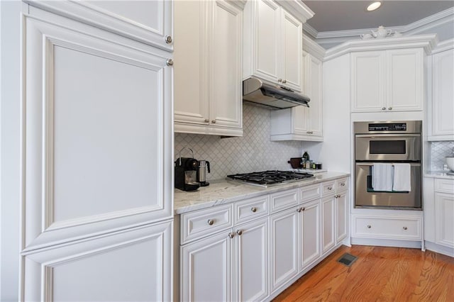 359 Alderwood Ln, Atlanta, GA 30328 - kitchen featuring appliances with stainless steel finishes, under cabinet range hood, white cabinetry, decorative backsplash, and light wood-type flooring
