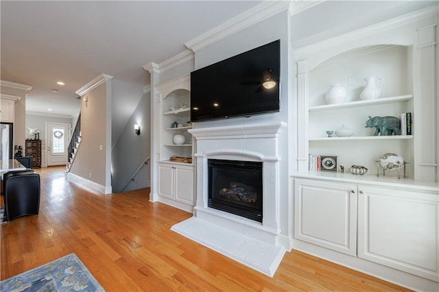 359 Alderwood Ln, Atlanta, GA 30328 - living area featuring a fireplace with raised hearth, built in shelves, light wood-type flooring, crown molding, and stairs