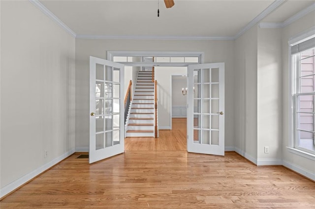 unfurnished room featuring french doors, ornamental molding, light wood-style flooring, and plenty of natural light