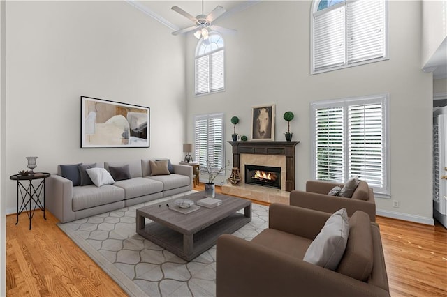 living area featuring ornamental molding, a fireplace, wood finished floors, and a towering ceiling