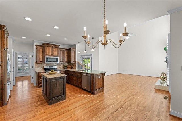 kitchen with crown molding, appliances with stainless steel finishes, a peninsula, and a healthy amount of sunlight