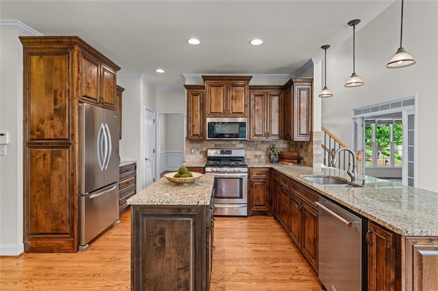kitchen featuring stainless steel appliances, a sink, light wood-style flooring, and a peninsula