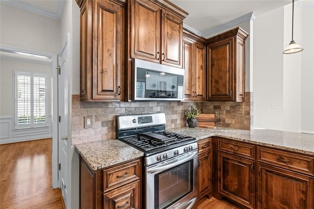 kitchen with crown molding, appliances with stainless steel finishes, light stone counters, and light wood-type flooring