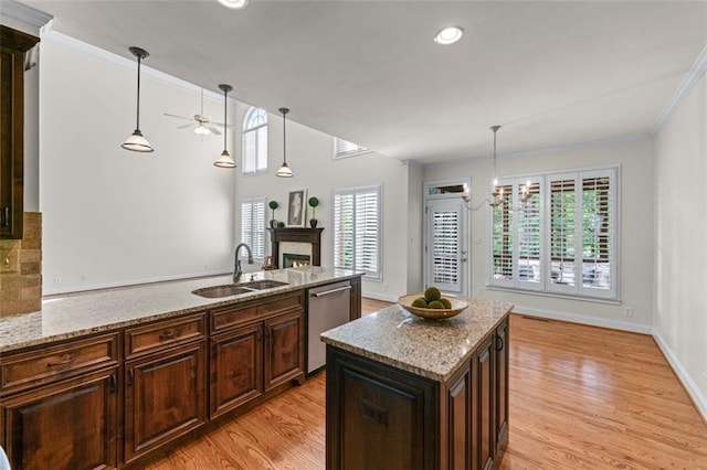 kitchen with a warm lit fireplace, a sink, a ceiling fan, a peninsula, and stainless steel dishwasher