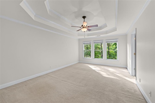 unfurnished room with crown molding, a raised ceiling, ceiling fan, and light colored carpet