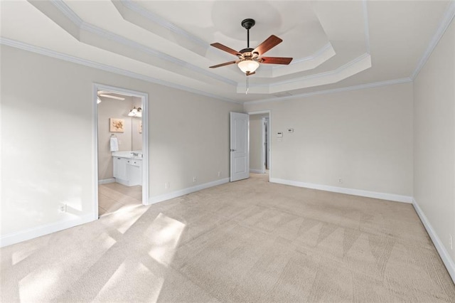 unfurnished bedroom with ornamental molding, a tray ceiling, and light carpet