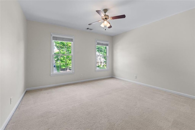 carpeted spare room with baseboards, a ceiling fan, and visible vents