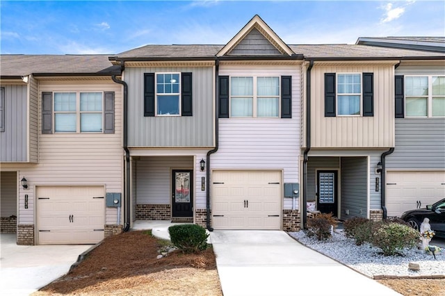 townhome / multi-family property with driveway, an attached garage, board and batten siding, and brick siding