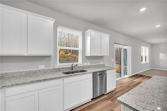 kitchen featuring light stone countertops, stainless steel dishwasher, sink, white cabinets, and light hardwood / wood-style flooring