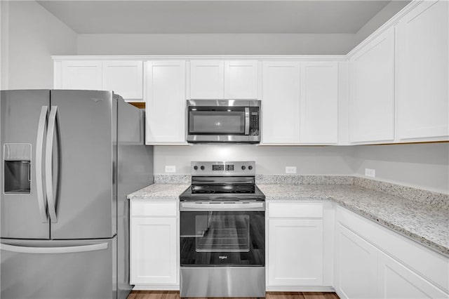 kitchen featuring white cabinetry, light stone counters, and appliances with stainless steel finishes