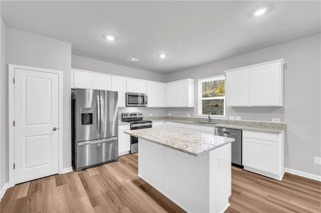 kitchen with sink, stainless steel appliances, a center island, and white cabinetry