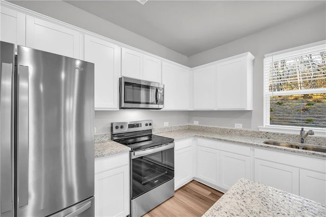 kitchen with white cabinets, stainless steel appliances, light hardwood / wood-style floors, and sink