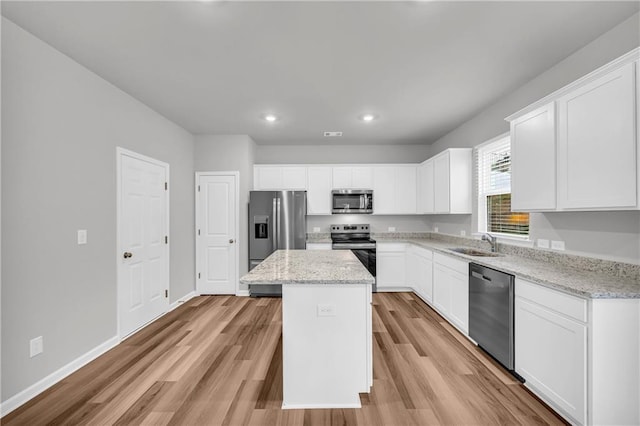 kitchen featuring a center island, sink, white cabinets, stainless steel appliances, and light stone counters