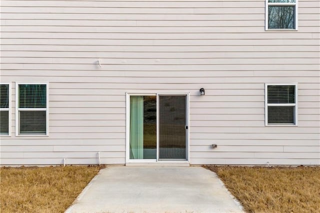 entrance to property featuring a patio area and a lawn