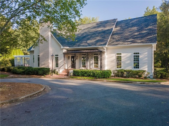 view of front of property featuring roof with shingles and a chimney