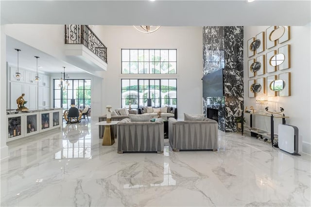 living area with a notable chandelier, marble finish floor, and a towering ceiling