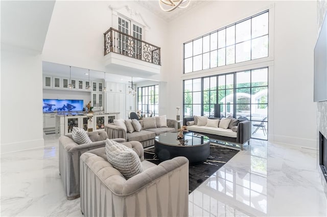 living area with baseboards, marble finish floor, a high end fireplace, and an inviting chandelier