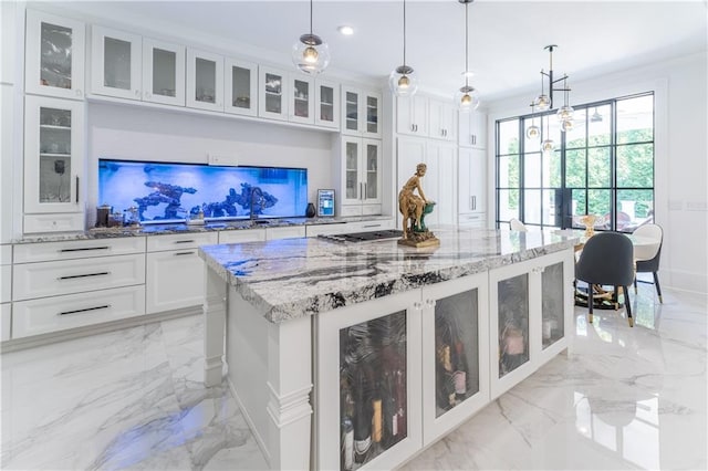 kitchen with marble finish floor, light stone counters, a kitchen island, white cabinetry, and stainless steel gas cooktop