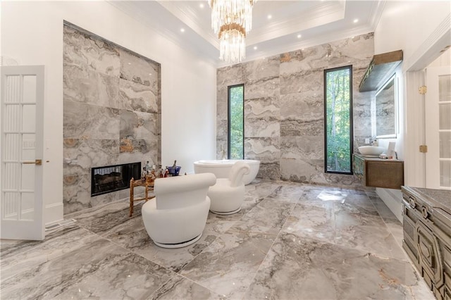 interior space with vanity, a fireplace, ornamental molding, a raised ceiling, and marble finish floor