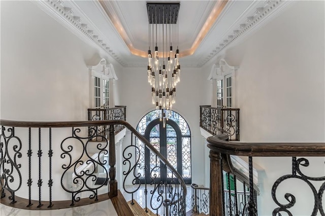 interior space with a tray ceiling, a high ceiling, ornamental molding, and a chandelier