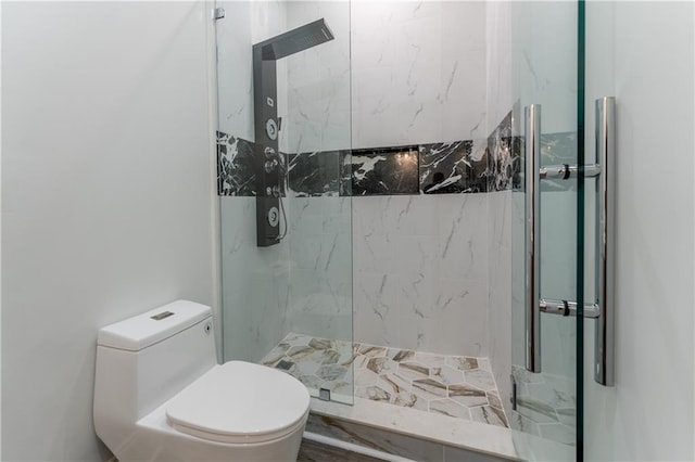 bathroom with a marble finish shower and toilet